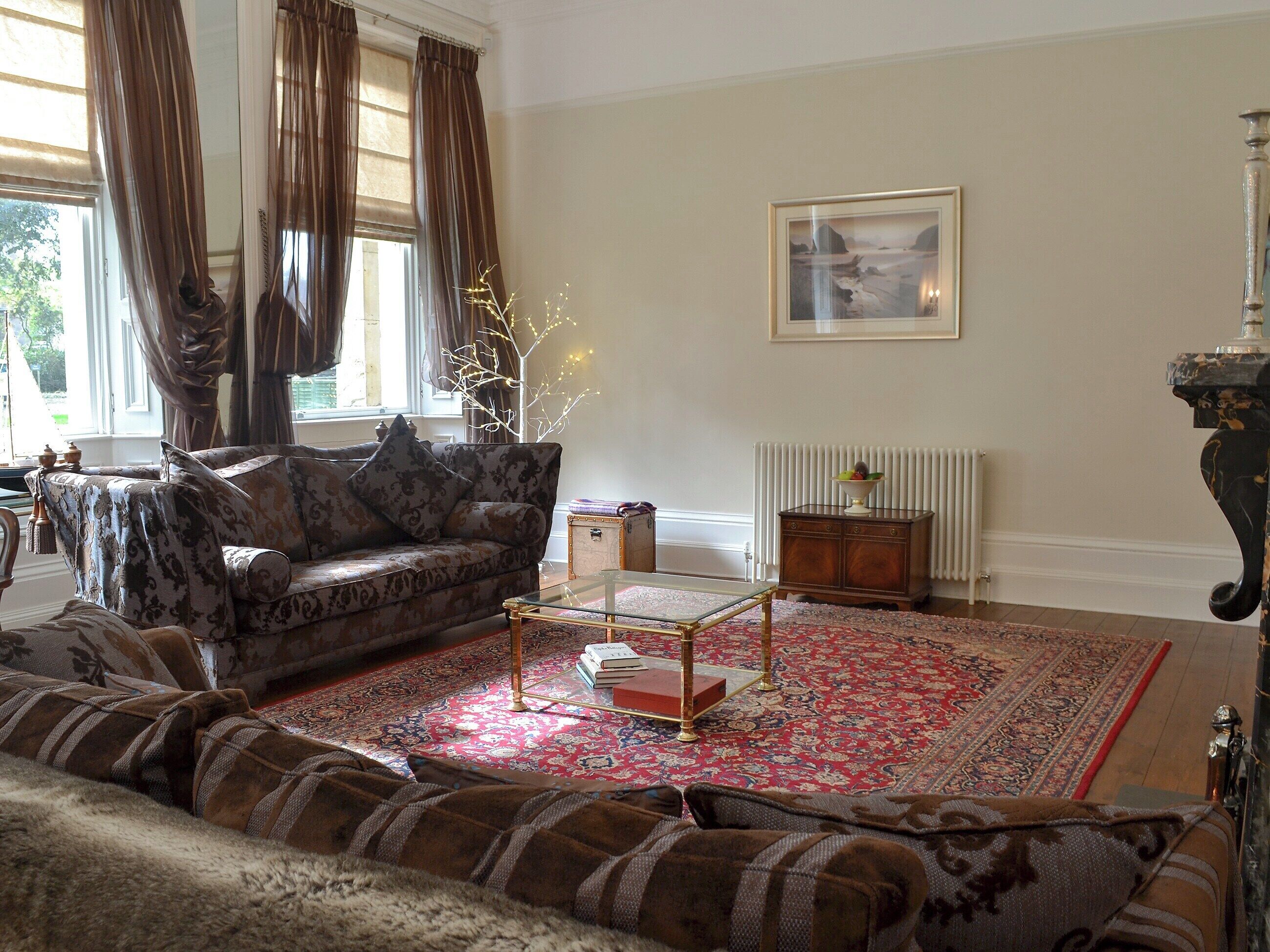 A living room with a sofa, a coffee table, and a patterned rug.