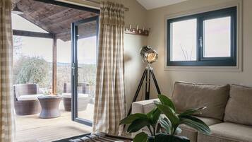 A room with a sliding glass door leading to an outdoor seating area, a floor lamp, a sofa, and a potted plant.