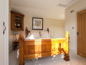 A bedroom with a wooden bed, a framed picture on the wall, and a cabinet above the bed. - 1 bedroom accommodation in Rudford, near Gloucester (Rudford, near Gloucester)