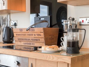 A kitchen counter with a coffee maker, a wooden crate labeled 'Whole Sale Fruit & Veg', and a plate of sandwiches. - 1 bedroom accommodation in Rudford, near Gloucester (Rudford, near Gloucester)