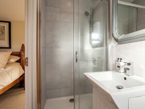 A modern bathroom with a glass-enclosed shower, a white sink with a mirror, and a wooden bed in the adjacent room. - 1 bedroom accommodation in Rudford, near Gloucester (Rudford, near Gloucester)
