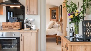 A modern kitchen with wooden cabinets, a built-in oven, and a coffee machine. - 1 bedroom accommodation in Rudford, near Gloucester (Rudford, near Gloucester)