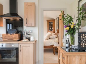 A modern kitchen with wooden cabinets, a built-in oven, and a coffee machine. - 1 bedroom accommodation in Rudford, near Gloucester (Rudford, near Gloucester)