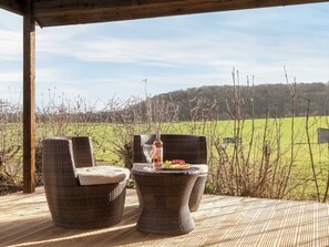 A covered outdoor seating area with wicker furniture and a table set with a bottle and glasses. - 1 bedroom accommodation in Rudford, near Gloucester (Rudford, near Gloucester)
