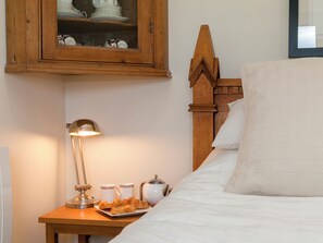 A neatly made bed with white linens, a bedside table with a lamp, a tray with croissants, and a cup and mug. - 1 bedroom accommodation in Rudford, near Gloucester (Rudford, near Gloucester)