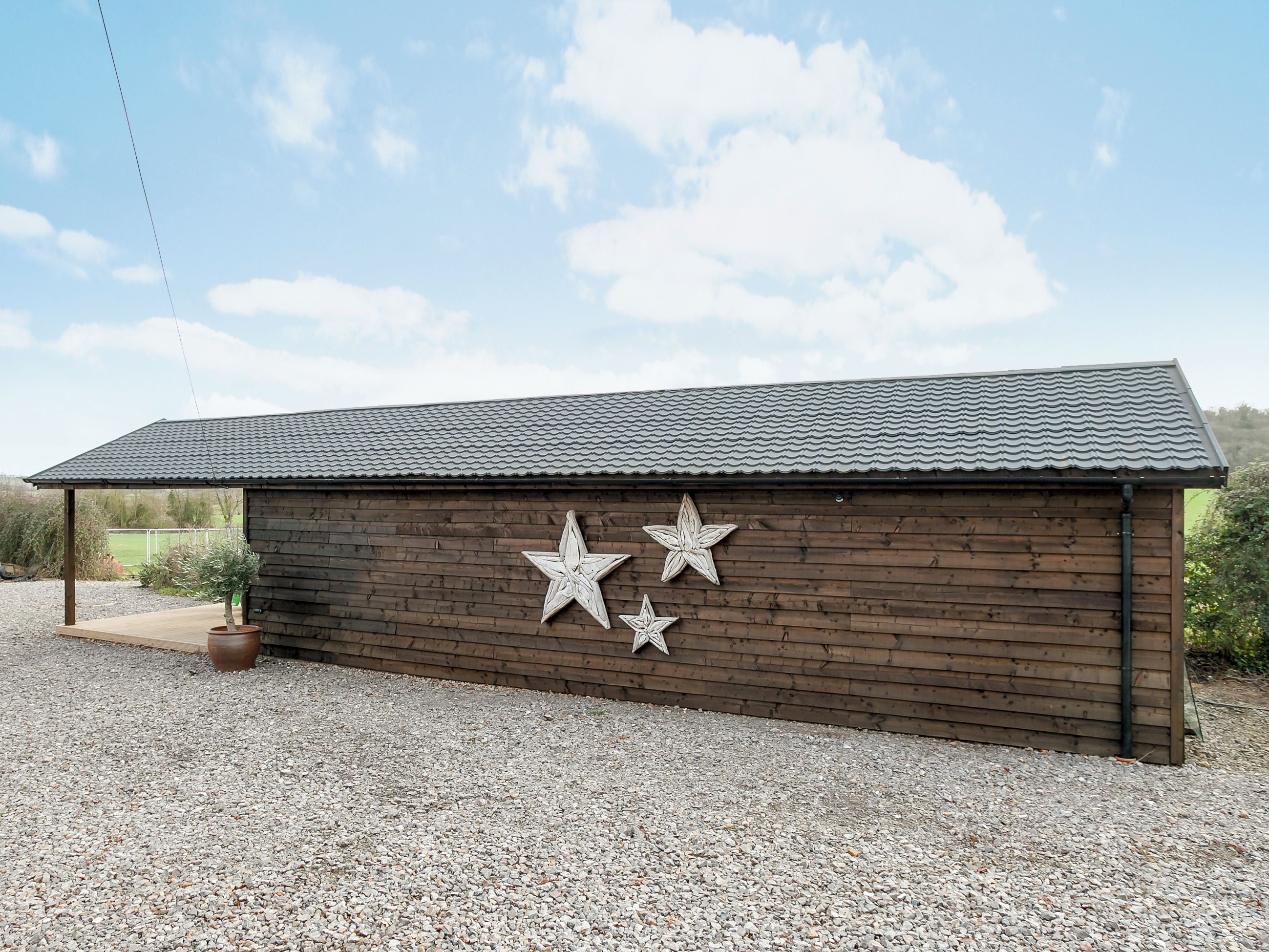 A wooden building with a metal roof and three star decorations on the side.