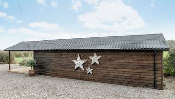 A wooden building with a metal roof and three star decorations on the side.