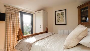 Una camera da letto con un letto, una finestra con tende, un termosifone, un quadro incorniciato e un armadio.