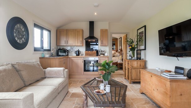 A spacious living area with a sofa, a coffee table, and a TV. - 1 bedroom accommodation in Rudford, near Gloucester (Rudford, near Gloucester)