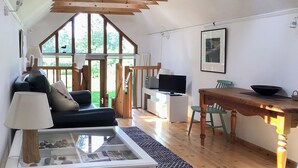 A spacious living area with a sofa, a coffee table, a TV, and a dining table. - 1 bedroom accommodation in Hoe, near Dereham (Hoe, near Dereham)