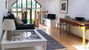 A spacious living area with a sofa, a coffee table, a TV, and a dining table.
