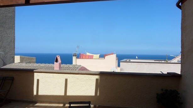 A balcony with a view of the sea, a table, and a chair. - Historic house 3 bedrooms 3 bathrooms with panoramic terrace (CASTELSARDO)
