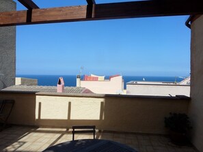 Un balcon avec vue sur la mer, une table et une chaise.