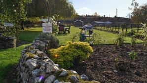 A garden with a stone wall, a grill, and a sign prohibiting dogs. - Dairy Cottage - UKC3735 (Foxley, near Fakenham)