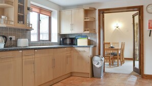 A kitchen with wooden cabinets, a microwave, and a trash bin. - Dairy Cottage - UKC3735 (Foxley, near Fakenham)