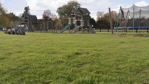 A playground with a slide, climbing structures, and a small wooden house. - Stable Cottage 3 - UKC3742 (Foxley, near Fakenham)
