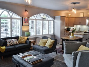 A modern living room with two sofas, a coffee table, and a dining area with a kitchen in the background. - 3 bedroom accommodation in Rothbury (Rothbury)