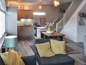 A modern kitchen with white cabinets, a wooden dining table, and a staircase leading to a loft. - 3 bedroom accommodation in Rothbury (Rothbury)