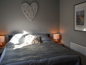 A bedroom with a large bed, two bedside lamps, a heart-shaped wall decoration, and a framed picture on the wall. - 3 bedroom accommodation in Rothbury (Rothbury)