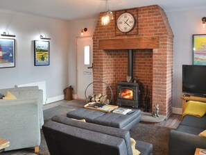 Ein Wohnzimmer mit Kamin aus Backstein, einer Couch, einem Fernseher und gerahmten Bildern an der Wand.