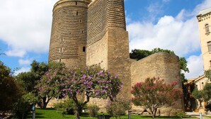 Un castell de pedra històric amb dues torres destacades i un jardí ben cuidat amb arbres florides.