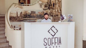 Taulell de recepció a l'Hotel Soffia, amb un mural de paisatge urbà de fons.
