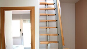 Una escalera con escalones de madera y barandillas de metal que lleva a una habitación con una cama y un ventanal.