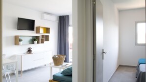 Una sala de estar moderna con un sofá, un televisor, un mueble blanco y una pequeña mesa con una cesta.