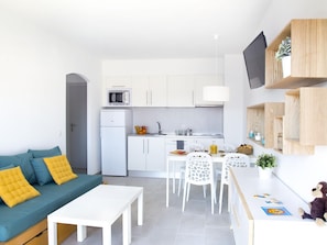 A modern kitchen with white cabinets, a microwave, and a refrigerator. There is a dining area with a white table and chairs. - Apartments with swimming pool. Ref. Estartit Comfort-46 (Estartit)