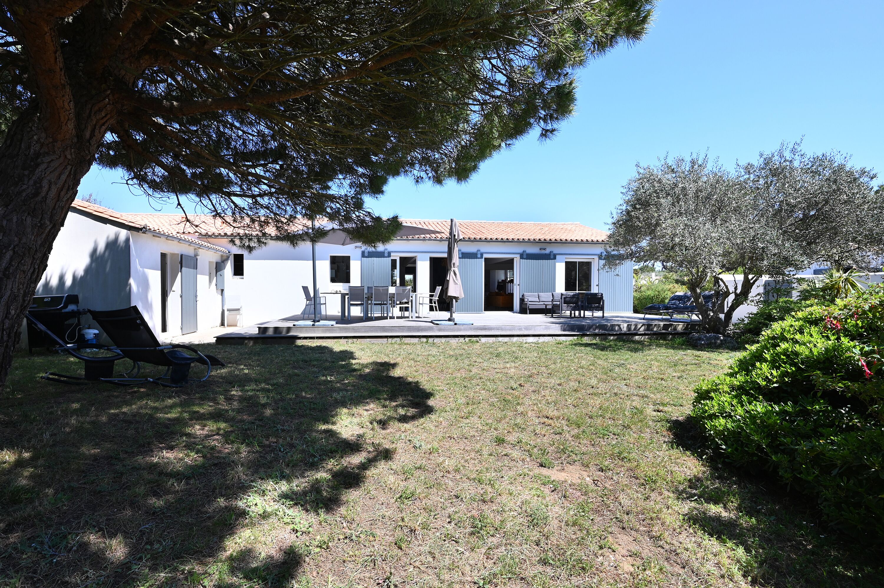 A white building with a tiled roof, a covered patio area, and a lawn.