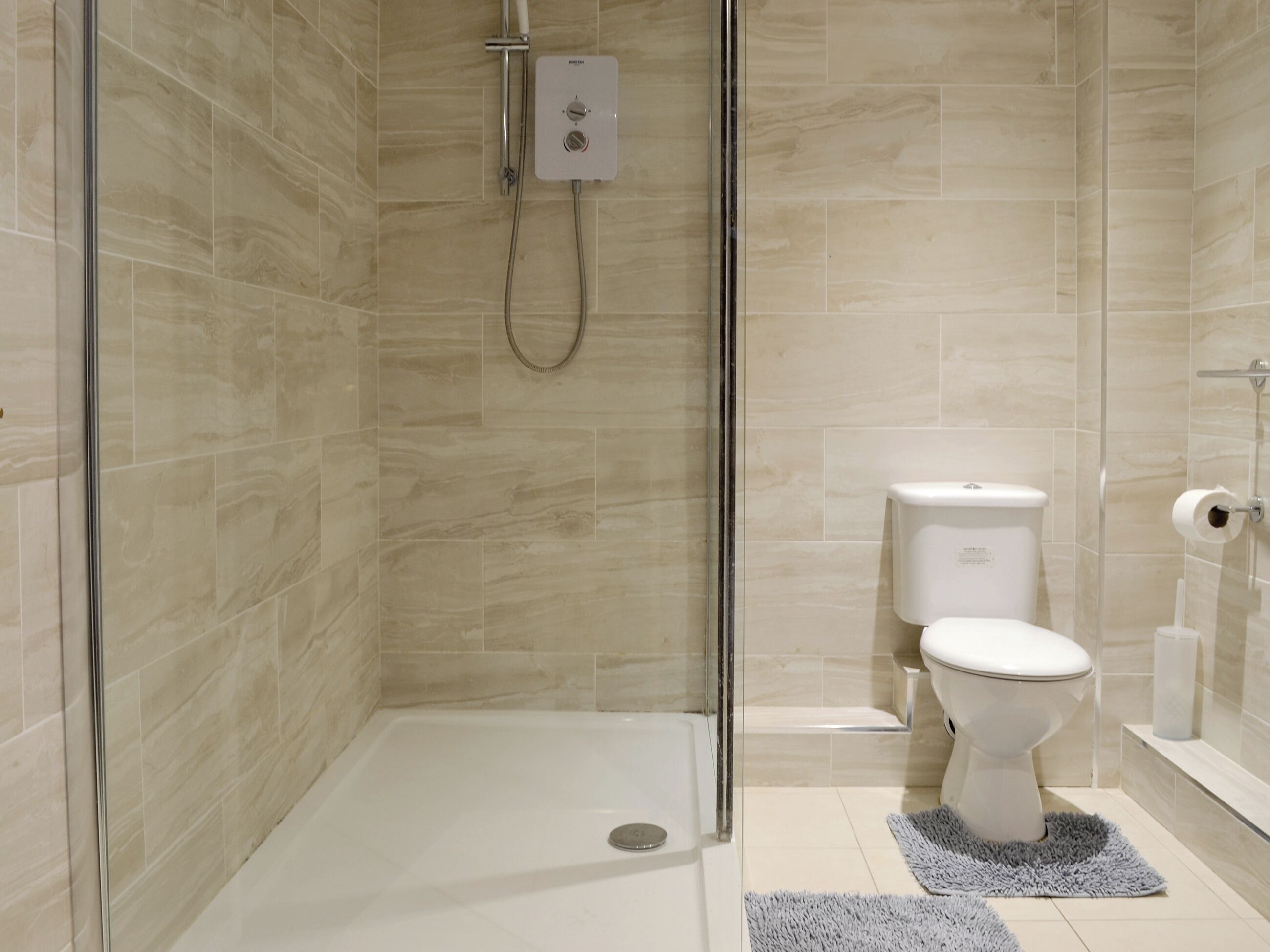 A modern bathroom with a glass shower enclosure, a toilet, and a bidet.