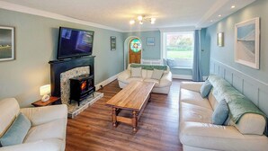 Een woonkamer met een open haard, een televisie en een zithoek.