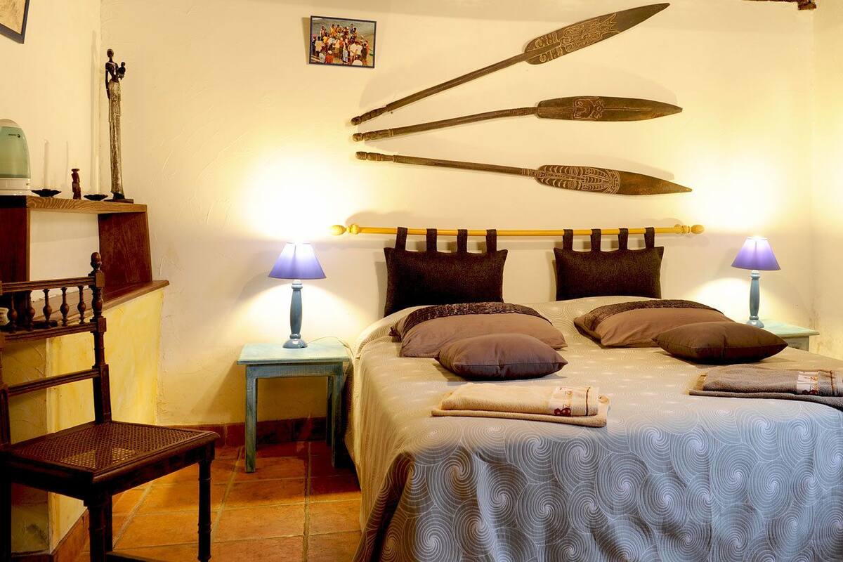 Une chambre à coucher comprenant un lit, deux tables de chevet, une chaise et une étagère fixée au mur.