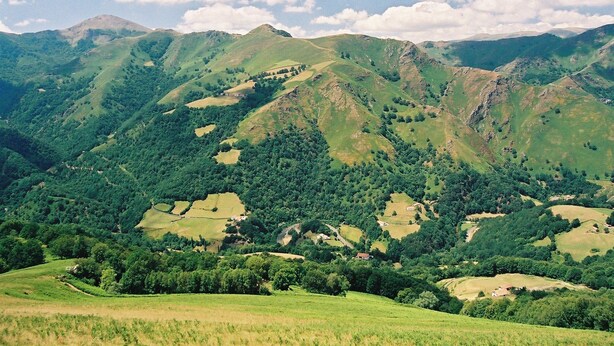 A panoramic view of a mountainous landscape with rolling hills, scattered trees, and a clear sky. - Chambres d'Hôtes Idiartekoborda (Saint-Etienne-de-Baigorry)