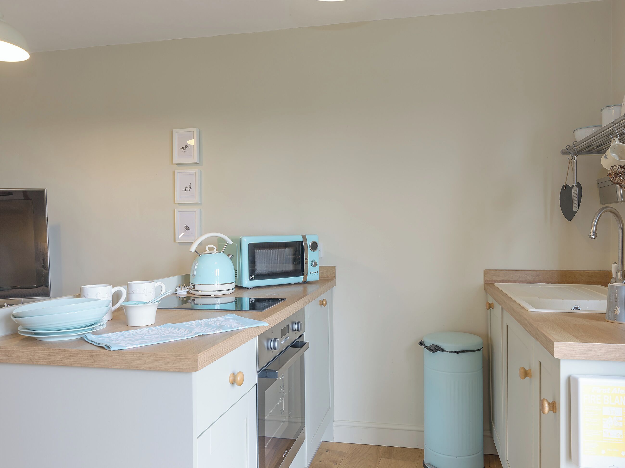 A compact kitchen with a microwave, kettle, and stacked dishes.