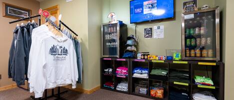 A clothing rack with various shirts, a vending machine with snacks, and a television on the wall.