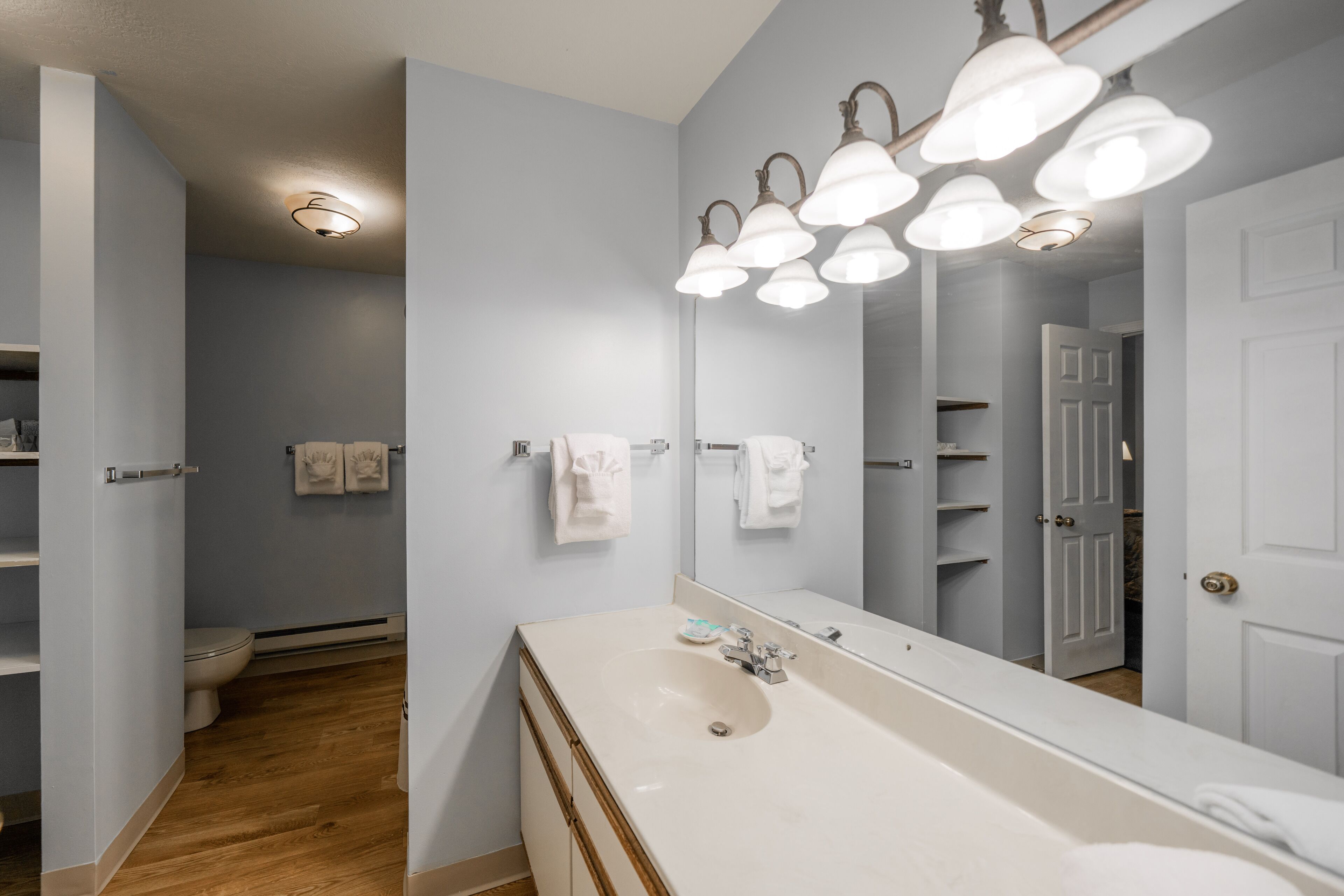 Une salle de bain avec un grand miroir, un lavabo et des toilettes.