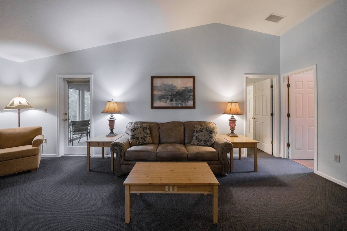 A living room with a sofa, two lamps, a coffee table, and a painting on the wall.