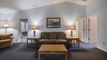 A living room with a sofa, two lamps, a coffee table, and a painting on the wall.