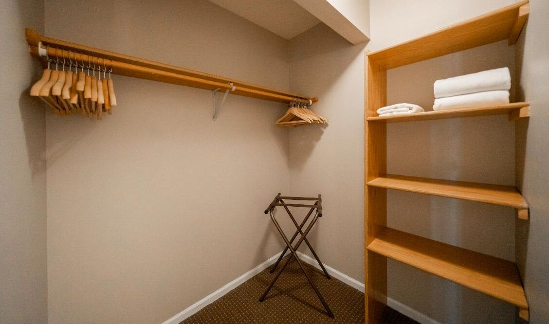 Een inloopkast met houten planken, een droogrek en knaakruimte.