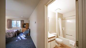 Ein Schlafzimmer mit Bett, Schreibtisch und Stuhl. Es gibt ein Badezimmer mit Toilette, Waschbecken und Dusche.