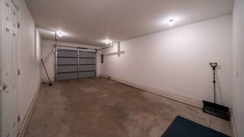 Eine saubere, leere Garage mit Betonboden, geschlossenem Garagentor und einem an der Wand angelehnten Besen.