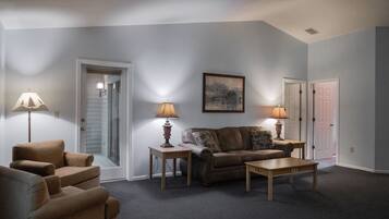 A living room with a sofa, two armchairs, a coffee table, and two lamps.