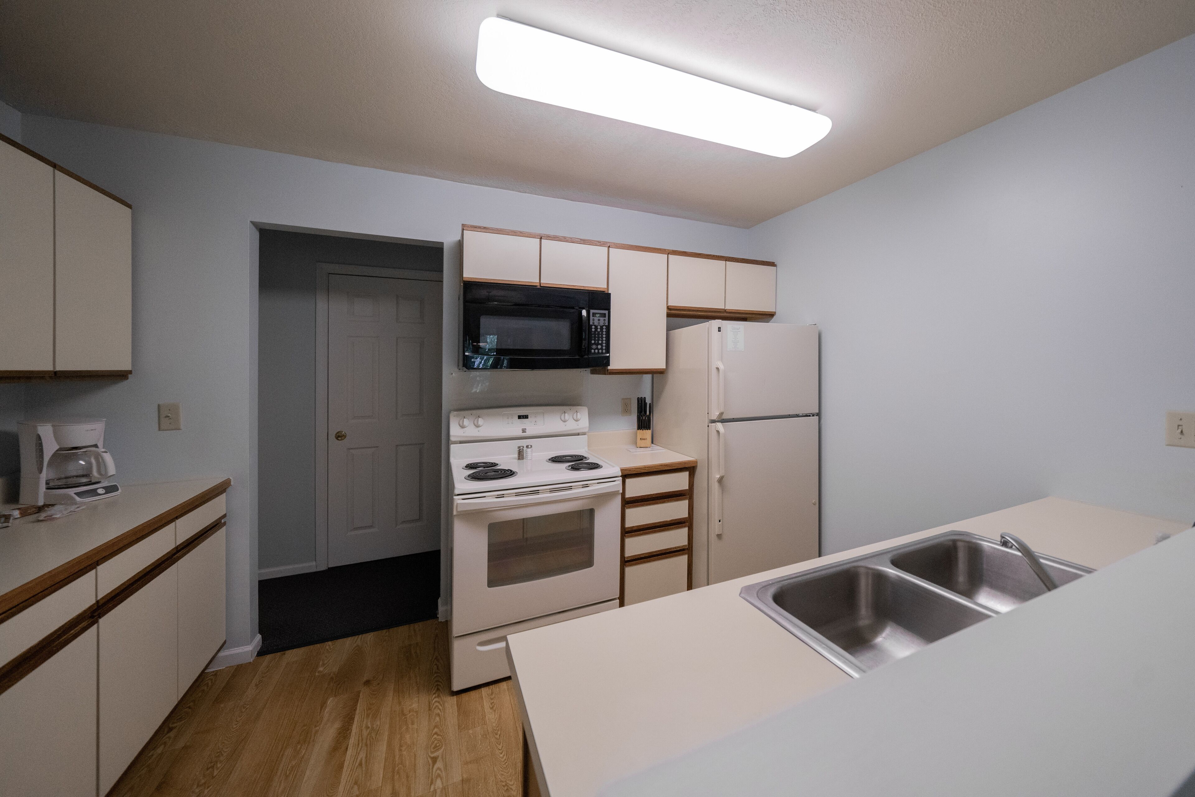 A compact kitchen with white cabinets, a microwave, a stove, and a refrigerator.