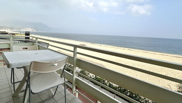 Un balcón con mesa y sillas que da a una playa.
