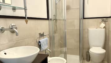Un bagno con un lavandino bianco grande, cabina doccia in vetro e un water.