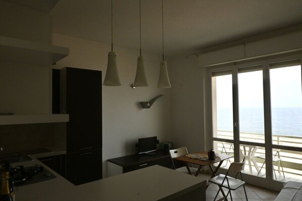 A modern kitchen with a dining area, a TV, and a view of the sea. - M210 - Marcelli, three-room apartment facing the sea with breathtaking views (Marcelli)
