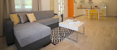 A modern living room with a grey sofa, a white coffee table, and a patterned rug.