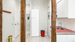 Cocina compacta con armarios blancos, encimera roja y pileta de acero inoxidable.