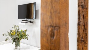 Una habitación moderna con un televisor de pantalla plana montado, un florero de vidrio con flores amarillas y un marco de puerta de madera.